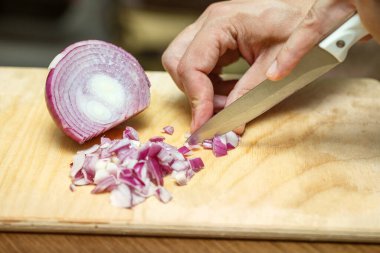 Soğan dilimliyorum. Aşçının elleri bıçağı dikkatlice tutuyor ve soğanı kesiyor. Evde yemek pişirmek.