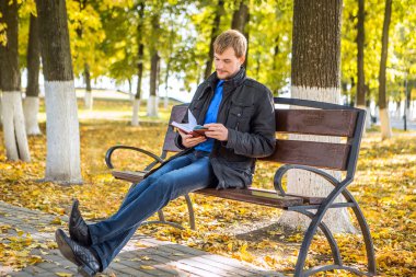 Şehir Parkı kitap ile oturan bir adam