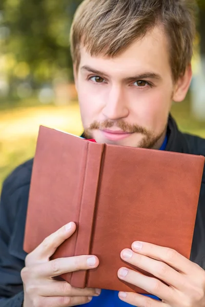 En man sitter med boken i stadsparken — Stockfoto