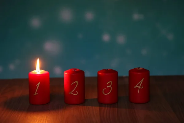 1.Advent. Red Advent candles stand on a wooden floor.