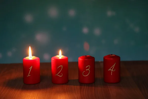 2.Advent. Red Advent candles stand on a wooden floor.