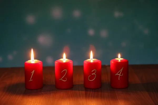 4.Advent. Red Advent candles stand on a wooden floor.