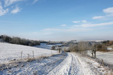 Karlı tarlaları ve mavi gökyüzü olan kış manzarası.