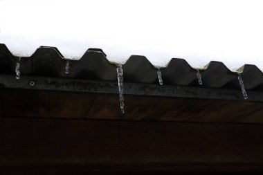 Çatıdaki kar erir ve buz saçakları oluşturur..