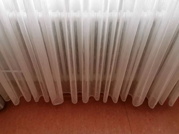 Una tenda bianca trasparente copre il radiatore — Foto Stock