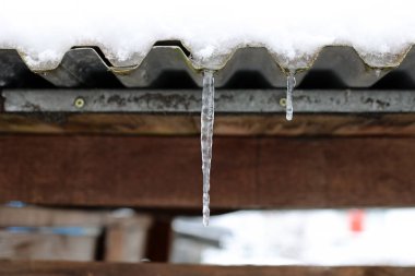 Çatıdaki kar erir ve buz saçakları oluşturur.