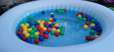 Multicolored balls float in the bubbling water of an inflatable pool.