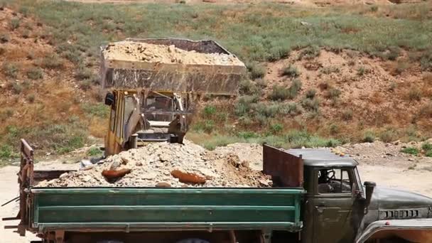 Excavator loading heavy duty dumper truck with rocks — Stock Video