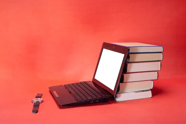 laptop and stack of books on yellow background