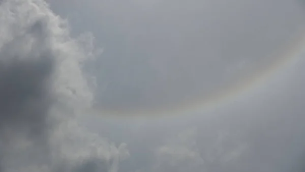 Sun\'s halo creates a rainbow pattern optical illusion in rain clouds