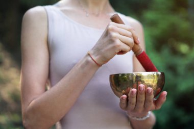 Nilüfer pozisyonundaki kaseden gelen titreşimlerle meditasyon. Doğa yoga temalı eller ve bronz çatal bıçaklar. soul müzik enstrümanında