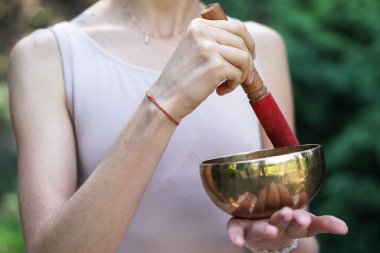 Nilüfer pozisyonundaki kaseden gelen titreşimlerle meditasyon. Doğa yoga temalı eller ve bronz çatal bıçaklar. soul müzik enstrümanında