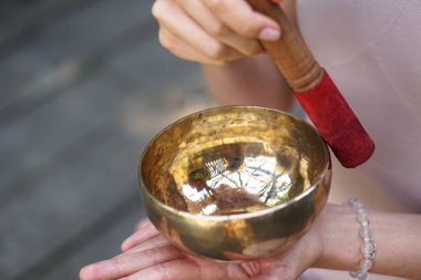Nilüfer pozisyonundaki kaseden gelen titreşimlerle meditasyon. Doğa yoga temalı eller ve bronz çatal bıçaklar. soul müzik enstrümanında