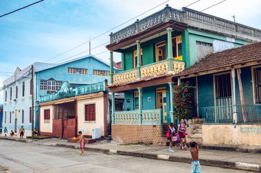 Baracoa, Küba - 25 Ekim 2019: Kübalı çocuklar renkli geleneksel evlerle sokakta oynuyorlar - gerçek Küba ruhunu hissediyorlar