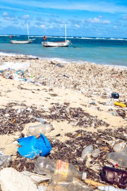 Tropikal denizin sahilinde boş bir Coca Cola şişesi. Kumsalda atık, mavi deniz altyapısı var. (Küba)