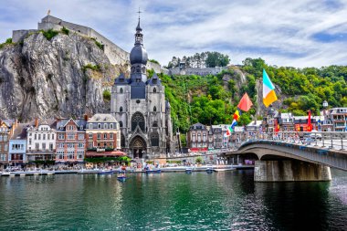 ADinant, Belçika - 19 Temmuz 2020: Meuse nehri, Wallonia, Belçika 'da Belçika bayrağı ve Notre-Dame Koleji Kilisesi üzerindeki kaleli tarihi Dinant kasabası