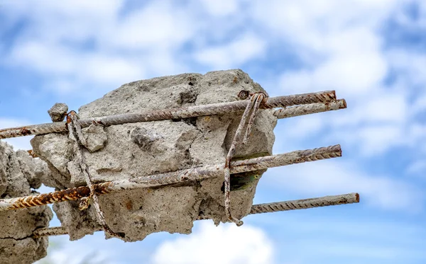 Barre di acciaio arrugginito in calcestruzzo. Pilastro di cemento danneggiato sul cielo blu . — Foto Stock