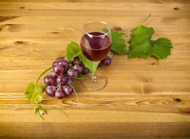 Kırmızı şarap cam ve ahşap masa üzerinde üzüm salkımı