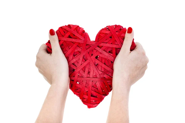 Las manos de la mujer sostienen el corazón de mimbre rojo — Foto de Stock