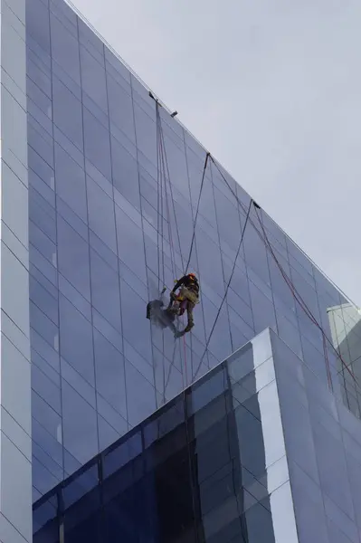 天井から吊るされた男が高いビルの窓を掃除し — ストック写真