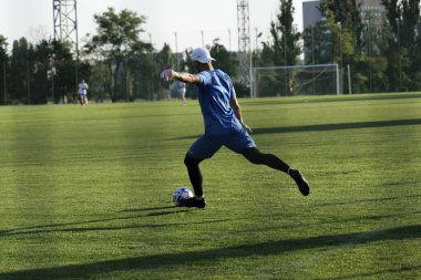 Futbol sahasındaki oyuncu topu atmak için antrenman yapıyor.