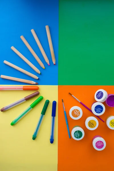 Colores planos de lápices de madera rodeados de bordes de colores arcoíris y dos pinceles con una gran cantidad de pinturas al agua . —  Fotos de Stock