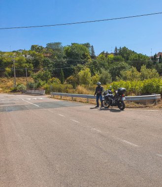 Mavi gökyüzünün altındaki akçaağaç yolunda motosikletli.