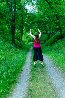 Kadın ormanda zıplıyor, dinleniyor.