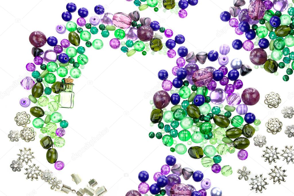 A layout of green and violet beads, sewing threads and other jewellery suppliers isolated on a white background. Selective focus.