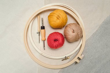 Nakış desenli çemberler, yumruk iğneleri, üç farklı kumaş üzerinde iplik topları. Yaratıcı nakış için araçlar ve ek malzemeler.