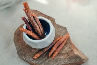 Meyveli şeker rulolarının, klasik ahşap çerçeve üzerinde kalan beyaz yüzlü bir fincan tabağında yakınlaştırılması. Şeker konsepti yok. Metin için yer.