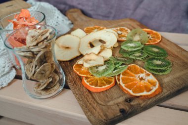 Kurutulmuş meyvelerin yerleşimi kivi, elma, mandalina, muz, balkabağı bazıları tahta tahtada, bazıları bardakta. Vegan sağlıklı tatlı konsepti.