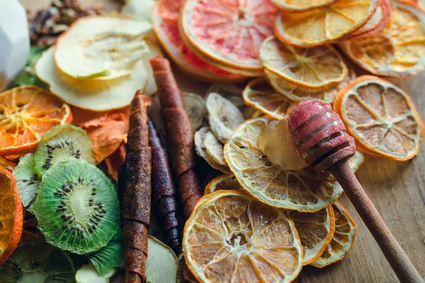 Ağaç tahtasına bal damlatan ballı, kurutulmuş portakal, kiwies, babanas, limon, mandalina, elma ve meyveli şekerlemeler serpiştirilmiş. Sağlıklı ve lezzetli tatlı konsepti.