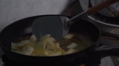 Kızarmış tavada kızgın yağda kızartılan çıtır manyok ya da sebze cipsi. Mutfak ortamında bir spatulayla karıştırılmış. Geleneksel ya da ev yemeği hazırlıklarına odaklan. Metni yakalar