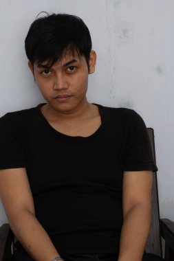 Asgari bir arka plan ve tarafsız bir ifadeyle evde oturan bir adamın basit bir portresi. Temiz kompozisyon ve doğal görünüş, yaşam tarzı, duygu ve kimlik gibi birçok kavram için bunu çok yönlü kılar.