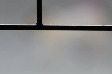 Siyah metal bir pencerenin silüetinin soyut mimari ayrıntıları parlak bulanık bir arka plana karşı. Minimalist endüstriyel tasarım ve güvenlik kavramı. Çizgiler, geometri ve yüksek kontrastlı ışıklandırma üzerine odaklanan iyi sanat fotoğrafçılığı.