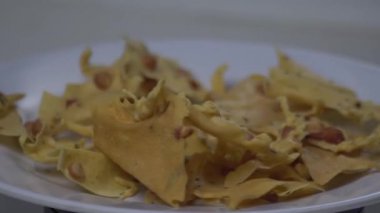 Beyaz bir tabakta servis edilen Rempeyek ya da Peyek adında geleneksel Endonezya fıstıklı krakerler. Fıstık ve limon yapraklı, kızarmış, çıtır çıtır, lezzetli atıştırmalıklar. Otantik sokak yemeği fotoğrafçılığı, çıtır çıtır kumaş, aşçılık için altın sarısı etnik aperatif..