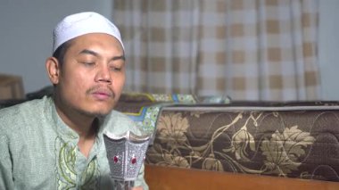 Gümüş tütsü yakıcısından çıkan aromatik dumanı yaymak için elini sallayan Müslüman bir adam. Otantik İslami yaşam tarzı, Ramazan geleneği ve evdeki ruhani atmosfer. Sinematik 4K kültürel video.