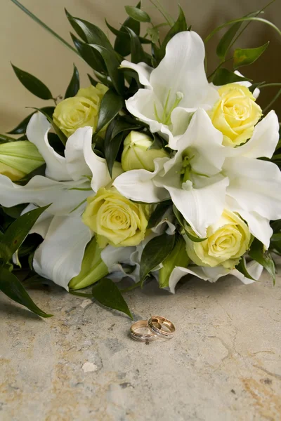 Svatební kytice z lilií a růží, zlaté snubní prsteny — Stock fotografie