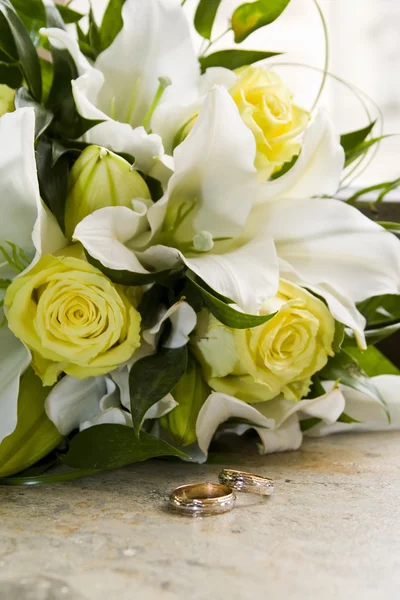 Brides bouquet of lilies and roses, gold wedding rings — Stock Photo, Image
