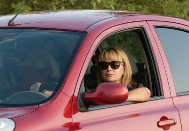 Parlak kadın kırmızı arabanın yanında.