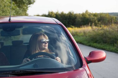 Parlak kadın kırmızı arabanın yanında.