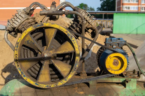 Old belt-driven diesel power generator in oil drips on a green fuel tank