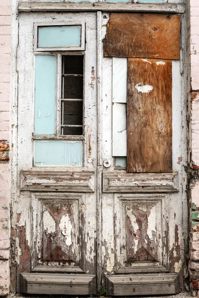 Old double-double doors with no part of the glass. Inside there is a metal lattice and a brick wall