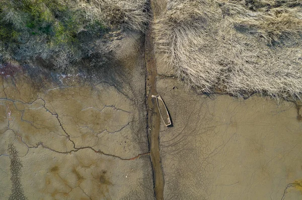 Kış sonunda eski kurumuş bir gölet ve kırık bir tekne.