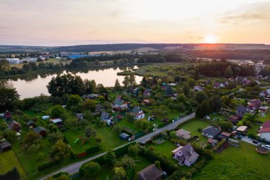 Yazın gün batımında bir balıkçıyla kır evi manzarası.