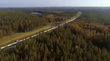 Güneşli bir gün, yaz. Bir rota, yol ve biraz üzerinde bir kuadrokopter uçuşu. Arabalar yol boyunca gider. Yeşil Orman. Göl kıyısında Lakeblue Lakewater yol kenarı onarımı