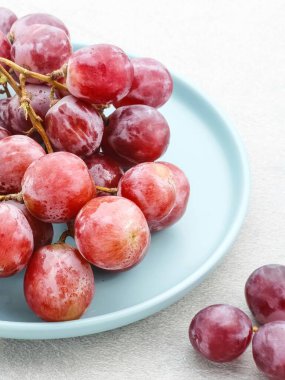 Gri arka planda servis edilen taze ve tatlı kırmızı üzümler. Seçici odak resmi.