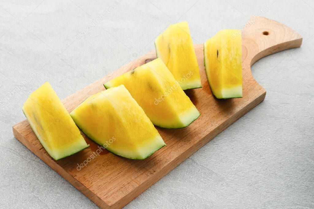 Slice yellow watermelon or semangka kuning on grey background. Selective focus, close up.