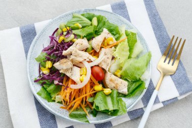 Yeşil yapraklı yeşil salata sebzeyle kızarmış tavuğu karıştırır. Gri masada servis edilmiş. Seçici odak resmi.